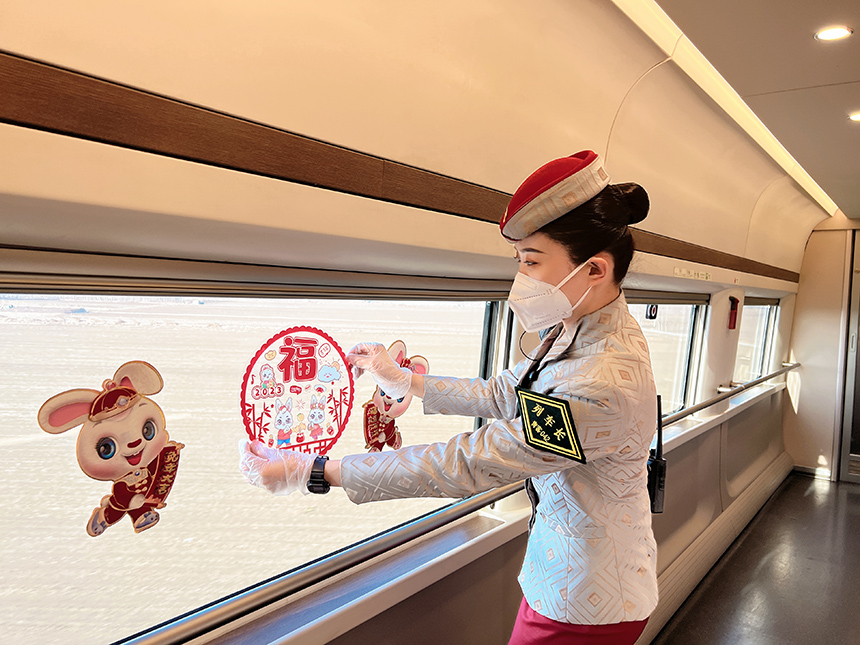 G204次列車長張京在車廂內(nèi)張貼兔年吉祥窗花。陳俊鳴攝