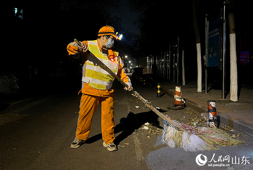 王海菊借著路燈光開始清掃道路。人民網(wǎng) 劉祺攝