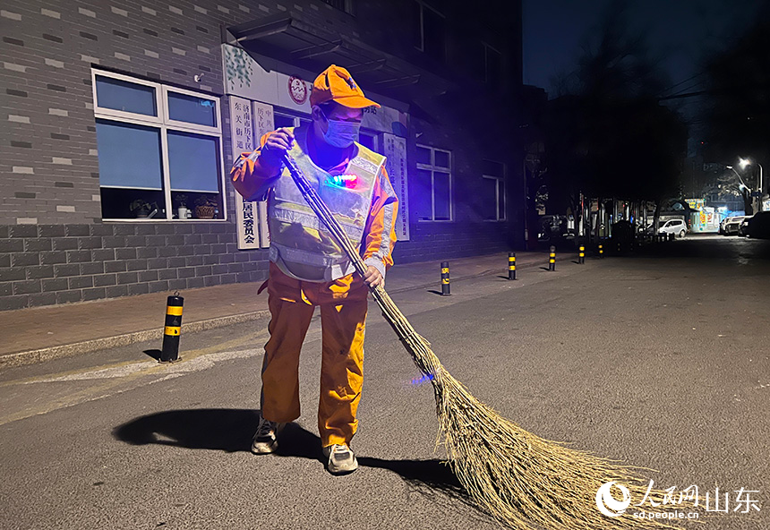 王海菊借著路燈光開始清掃道路。人民網(wǎng) 劉祺攝