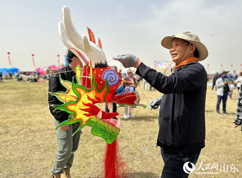 風箏比賽參賽者正在整理龍頭蜈蚣風箏，為放飛做準備。人民網(wǎng) 喬姝攝