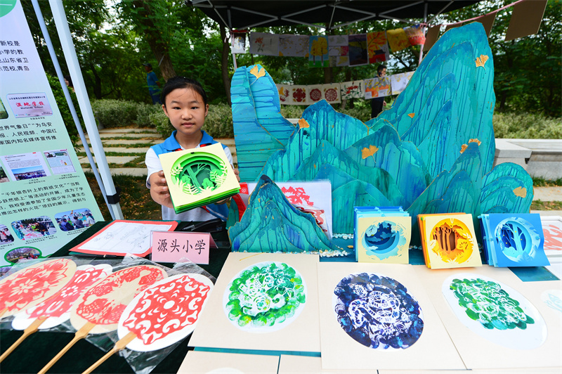 一名源頭小學(xué)的學(xué)生在展示生態(tài)剪紙作品。王海濱攝