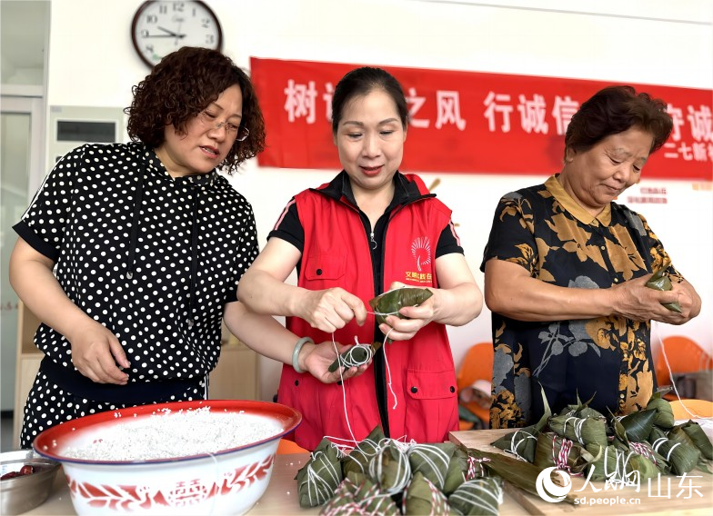 6月21日，濟(jì)南市市中區(qū)二七新村街道建南社區(qū)舉行“鄰里家和美，端午祝安康”活動(dòng)。社區(qū)居民聚在一起包粽子、迎端午。人民網(wǎng) 喬姝攝