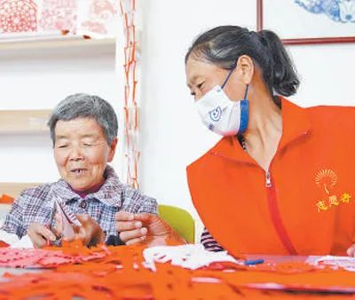 黃家峪村養(yǎng)老服務(wù)中心內(nèi)，志愿者在陪老人剪紙。新華社記者 郭緒雷攝