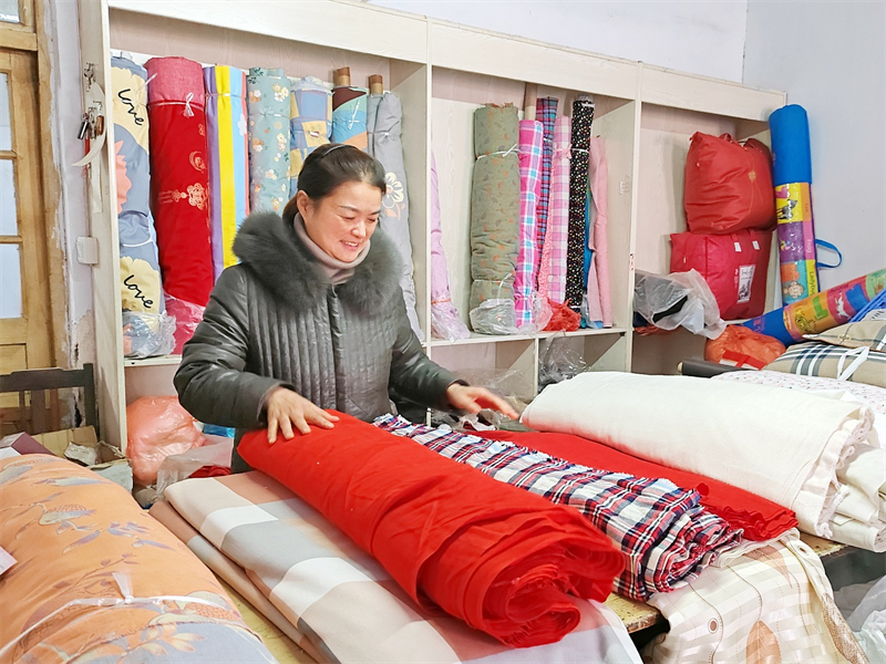圖為王素蕓在整理店內(nèi)銷售的布匹