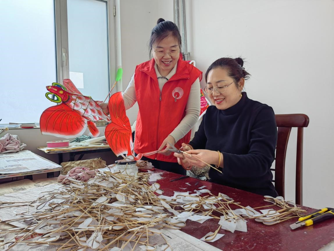 客戶經(jīng)理葛瑩（左）在工作間與楊明霞討論風(fēng)箏制作方法