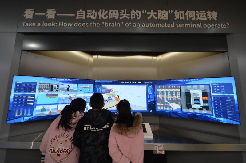 三名學(xué)生在體驗(yàn)自動(dòng)化碼頭“大腦”平臺(tái)。