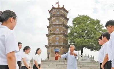 王建亮（中）為前來瞻仰烈士紀(jì)念塔的年輕人講解歷史。陳 彬攝