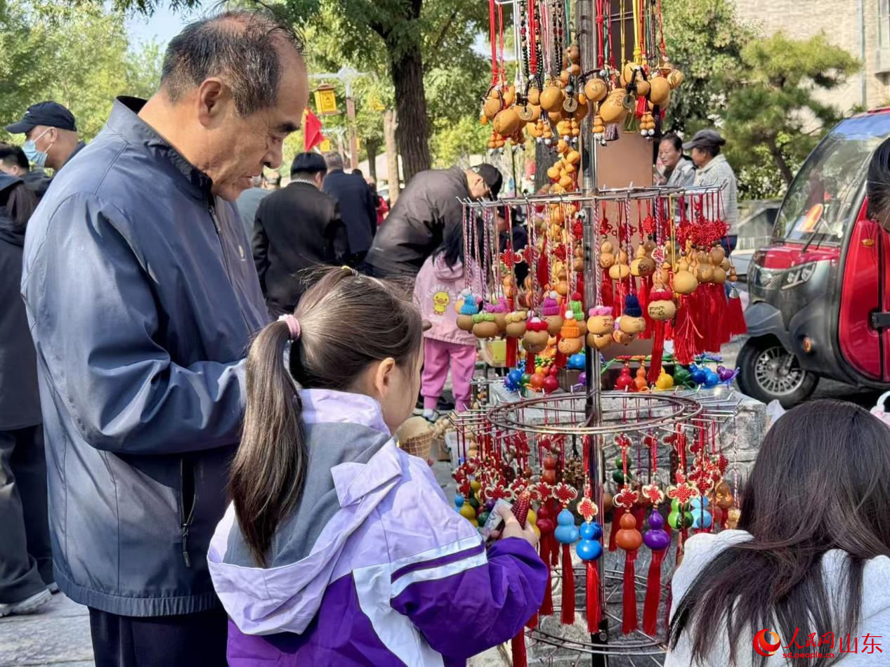 展位上葫蘆工藝品琳瑯滿目，游客正駐足選購。人民網(wǎng) 鄭昕橋攝