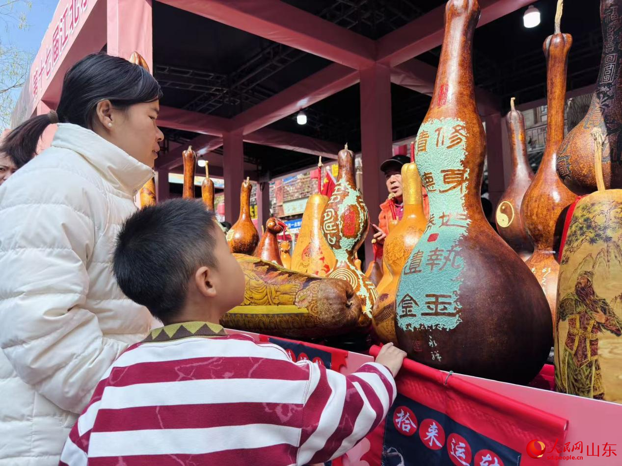 小朋友被琳瑯滿目的葫蘆工藝品吸引駐足。人民網(wǎng) 鄭昕橋攝