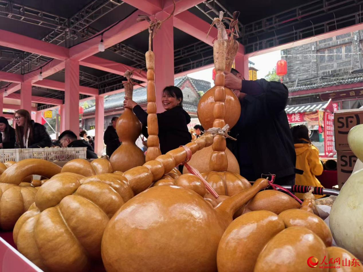 兩位攤主滿面笑容，正在認(rèn)真擦拭葫蘆工藝品。人民網(wǎng) 鄭昕橋攝