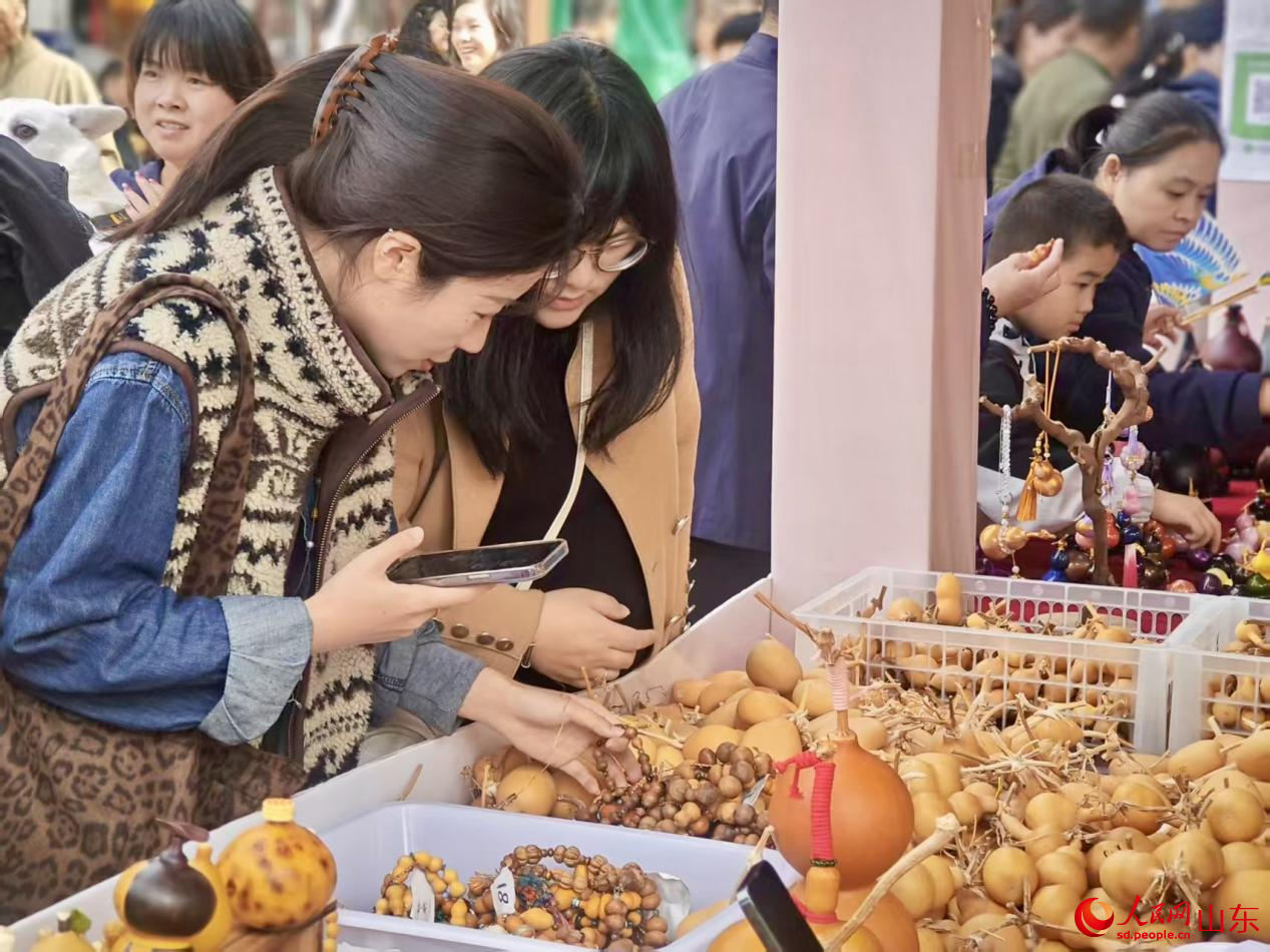 游客在琳瑯滿目的葫蘆工藝品展位前精心挑選。人民網(wǎng) 鄭昕橋攝