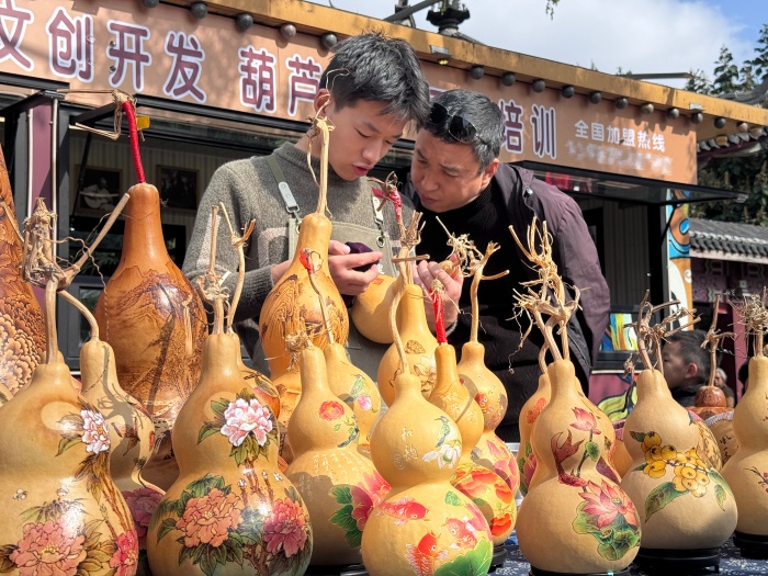 攤主正在講解葫蘆雕刻工藝。人民網(wǎng) 鄭昕橋攝