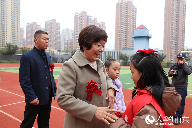 學生志愿者在簽到臺為老人佩戴胸花，老人臉上綻放出幸福燦爛的笑容。人民網(wǎng)記者 劉祺攝