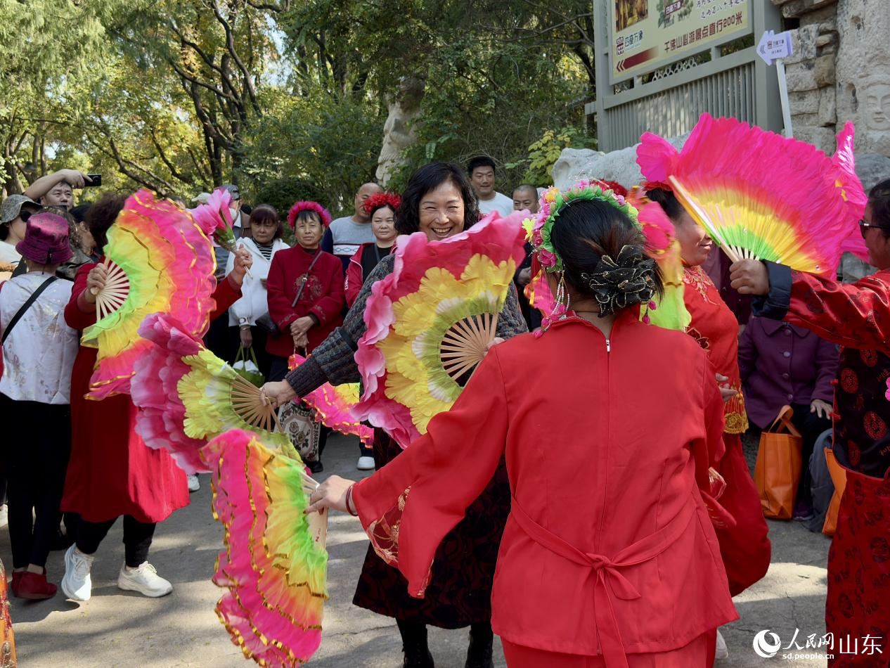 來(lái)自臨清的民間舞者彩扇飛揚(yáng)，一位游客被歡快氣氛感染，情不自禁加入其中。人民網(wǎng) 鄭昕橋攝