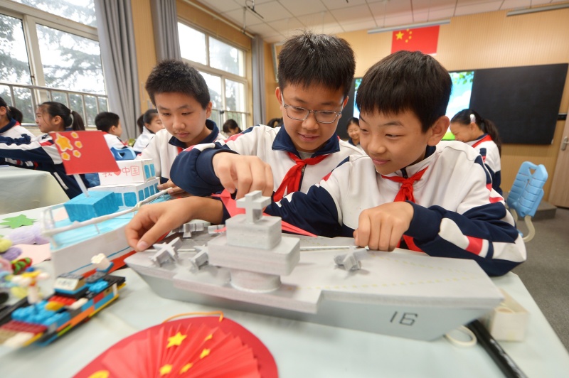 兩名學(xué)生在整理利用廢舊材料制作的航母模型。