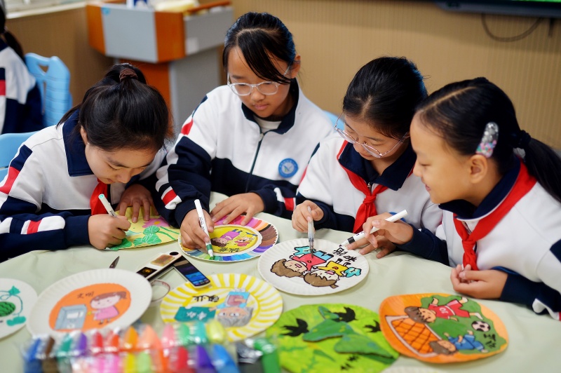 學(xué)生利用廢舊物品制作紙盤畫。