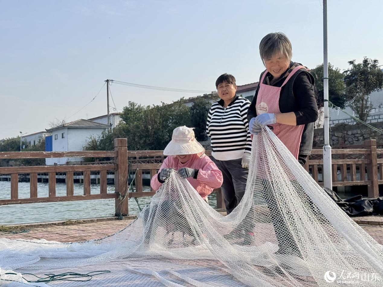 村民臉上洋溢著笑容，正在織捕魚網(wǎng)箱。人民網(wǎng) 鄭昕橋攝