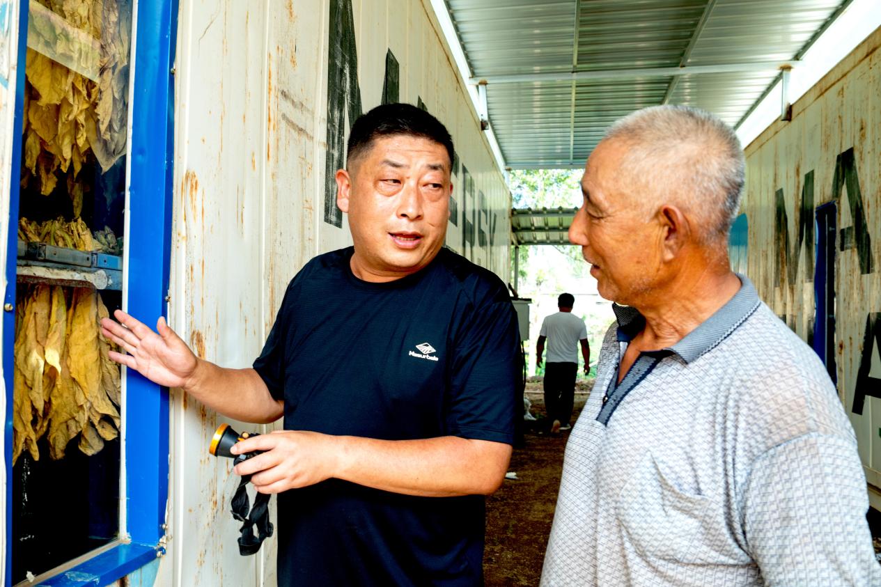 圖為技術(shù)員向司爐手講解熱泵烤房使用要點(diǎn)